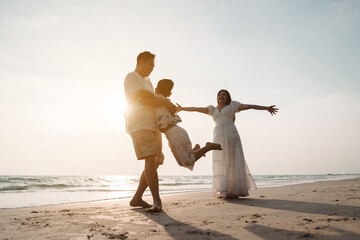 Fototapeta premium Happy asian family enjoy together on the beach in holiday vacation. Silhouette of the family holding hands enjoying the sunset on the sea beach. Happy family travel, trip family holidays weekend.