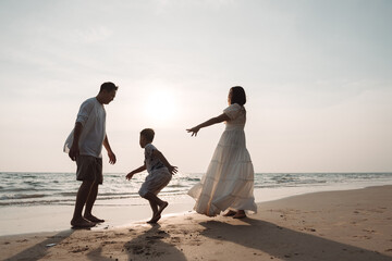 Happy asian family enjoy together on the beach in holiday vacation. Silhouette of the family holding hands enjoying the sunset on the sea beach. Happy family travel, trip  family holidays weekend.