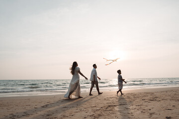 Happy asian family enjoy the sea beach together. father, mother and son having fun playing kite on...