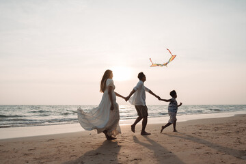 Happy asian family enjoy the sea beach together. father, mother and son having fun playing kite on...