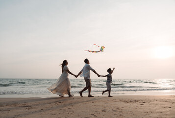 Happy asian family enjoy the sea beach together. father, mother and son having fun playing kite on beach in summer vacation on the ocean beach vacation time lifestyle concept.