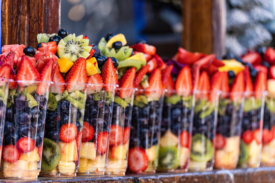 Close-up of rows of plastic cups filled with assorted fresh fruit on a shelf