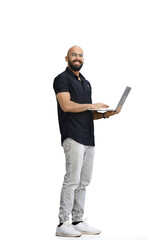 A man, on a white background, in full height, uses a laptop