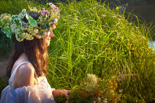 Celebration of Ivan Kupala with traditional wreath and fortune telling by the river at sunset