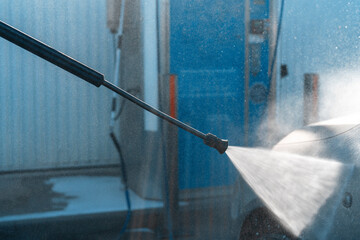 Power washing equipment cleaning a vehicle at a car wash facility in bright daylight