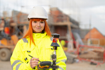 Female Construction site worker land surveyor  uses surveying equipment to measure and assess the...