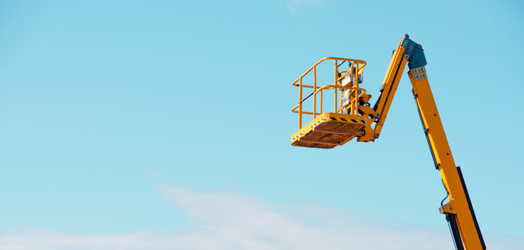 Elevated work platform extends into clear blue sky for maintenance tasks at construction site