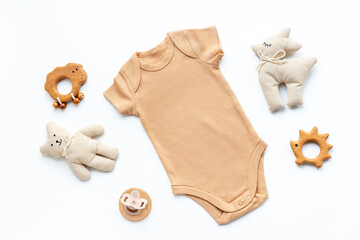 Flat lay with beige baby bodysuit and eco friendly toys on white background, top view