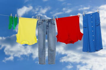 Different clothes drying on washing line against blue sky