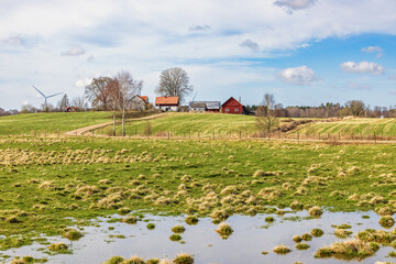 Standing water on a meadow at spring by a farmstead on a hill