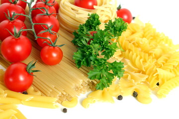 On a white background lie long straight spaghetti and pasta in the form of baskets with vegetables.