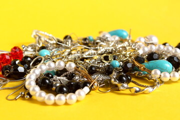A pile of women's jewelry lies on a yellow background.
