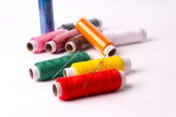 Colorful sewing thread set and needles isolated on background.
