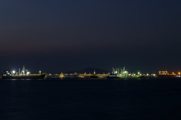 Obraz premium Seascape at night over lighting, crude oil floating station and bridge pipeline load and unloading oil and gas import export transportation global business,