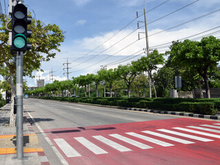 illuminated traffic light pole on sidewalk before zebra crosswalk on road