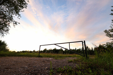 Old metal road close barrier gralve road with interesting sunset-pink color clouds.