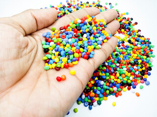 Plastic masterbatch mix color granules in open hand grip, polymer carrying colorful pigments isolated on white background, suitable for industrial plastic company profile product catalog design