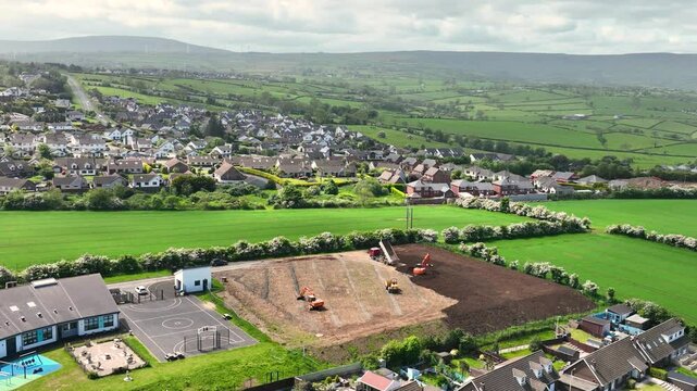 Slow motion aerial view of machinery at construction of sports fields Corran Integrated Primary School Larne N. Ireland 10-02-20 