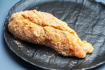 The process of making Corden Blue according to a traditional French recipe, ruw chicken breast is wrapped in breadcrumbs.