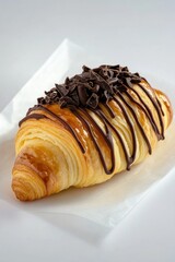 A chocolate-covered croissant sitting on a piece of paper, perfect for a coffee break or a dessert display