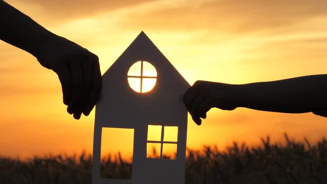 paper house ricky sunset. sunlight window. buying real estate living. House rent. happy family. paper house baby hands mom sunlight. holding hands together. mortgage. real estate concept. credit.