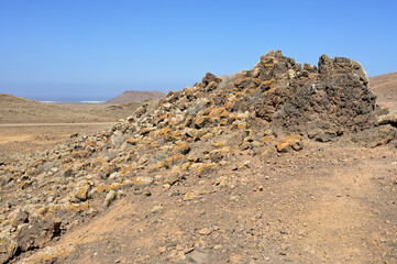 Hill of cooled Lava against blue sky seen during an excursion in volcanic landscape of the nature park Caminos Naturales, Fuerteventura, Canary Islands, Spain