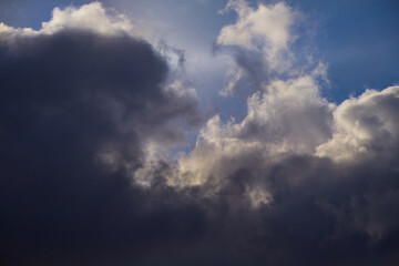 Fototapeta premium Clouds in various shades – from light to dark – create a stunning contrast against the blue sky. The majestic sky landscape is filled with natural dynamism and depth.