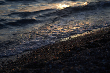 The sea at dusk. Water reaching the shore of a pebble beach in the afternoon sun. With space to copy. High quality photo