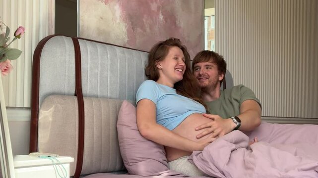 beautiful young couple in love man and pregnant woman in bed in the morning, enjoying each other. concept happy relationship