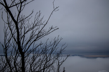 Winter cloudscape mountains view. Fog and mist on the sky with some dark clouds in a freezing morning air among the mountains and hills in Brasov, Romania