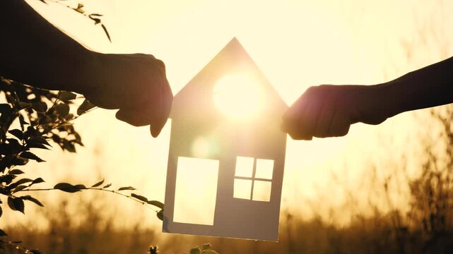 bright sunlight, holding house symbols hands, holding paper house sunset, cardboard cutouts house, houses family, friendly family, construction concept, friendly family holding paper house hands