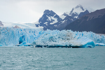 Perito Moreno famous glacier in Patagonia, EL Calafate, Argentina. Deep blue ice of the growing and moving glacier, stunning walls of ice and icebergs floating in the turquoise lake below the glacier 