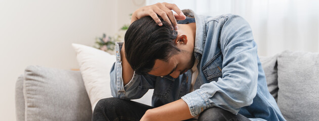 Depressed young men sitting in living room gloomy mood.