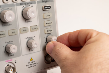 Hand adjusting settings on a digital oscilloscope
