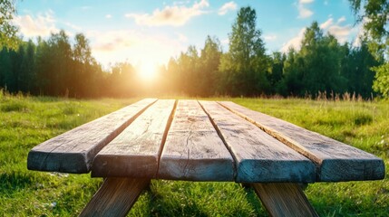 Fototapeta premium Wooden picnic table in a lush green field during sunset, evokes peace and relaxation in nature.