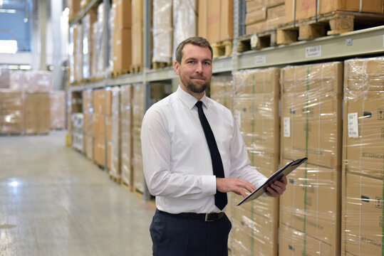portrait friendly businessman/ manager in suit working in the warehouse of a company - control of inventories
