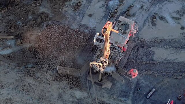 Aerial view from drone at Construction site features heavy machinery drilling ground and pumping concrete for foundation work