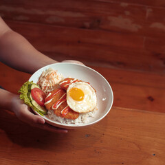 Chicken cutlet topped with a sunny-side-up egg, served on rice with vegetables at a warm, inviting restaurant setting