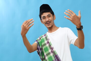 Fototapeta premium Asian muslim man asks join him, beckons with inviting hand hugs gesture. He is playful, flirtatious, inviting to come