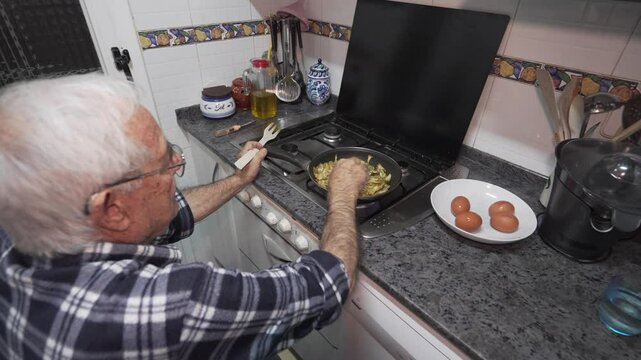old man alone cooking sitting on stool old man in his eighties in checked shirt