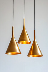 Fototapeta premium Three golden hanging lamps with a simple cone shape, against a white background