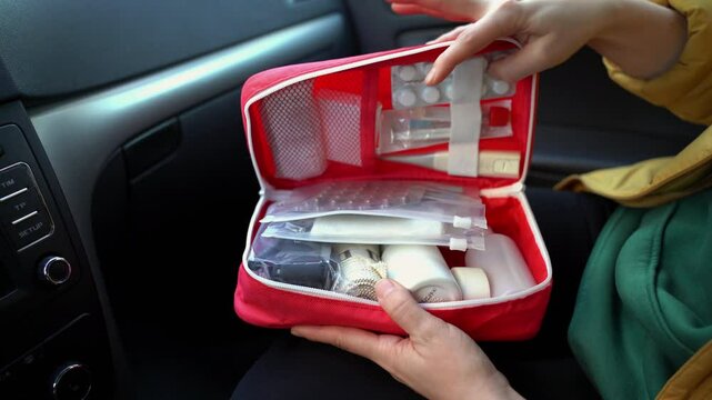 A vibrant red first aid kit is open inside a car, displaying a wellorganized assortment of essential medical supplies, readily accessible for any kind of emergencies that may arise