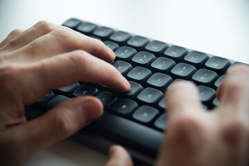 Close up of a man's hands on keyboard of lap top in the dark room, people working at home, modern white notebook. Internet, work, technology concept.