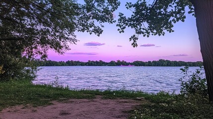 Peaceful lake sunset, trees framing view, distant lights