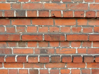 Obraz premium Historical masonry wall with decorative bands of alternating protruding brick layers, giving the facade a unique, artistic design.