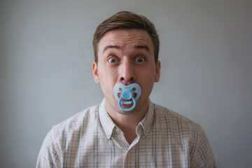 Man with a surprised face sucks a baby's pacifier.