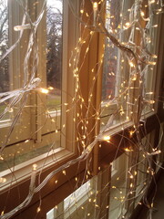The window in the home interior is decorated with bright decorative lamps for a festive mood. Photo taken on a mobile phone