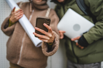 close up on male and female stand and use mobile phone outdoor