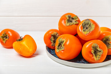 Persimmon on textured wooden background. Persimmon fruit. A piece of ripe, juicy, sweet persimmon fruit. Vegan. Orchard. Close-up. Space for text. Copy space.