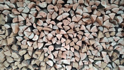 A close-up view of a neat stack of chopped firewood ready to burn, perfect for cozy winter nights.